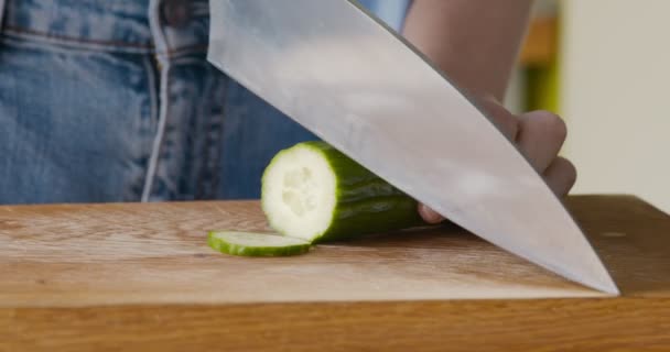 Gros plan de la femme tranchant du concombre frais sur une planche à découper — Video