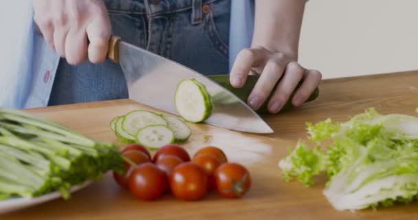 Kobieta cięcia świeżego ogórka do sałatki warzywnej w kuchni — Wideo stockowe