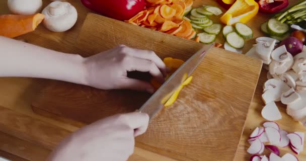 Жінка нарізає жовтий болгарський перець на дошці — стокове відео
