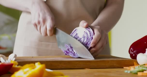 Mujer chef cortando repollo rojo fresco en el tablero de la cocina — Vídeos de Stock