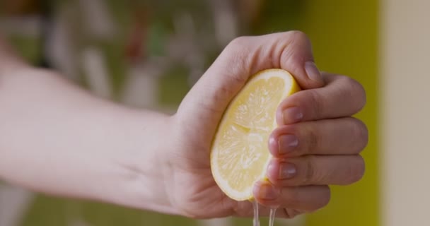 Vrouwelijke hand knijpen verse citroen helft, het maken van sap — Stockvideo