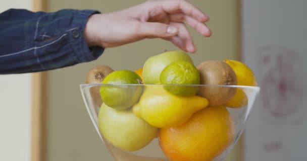 Jonge vrouw neemt verse appel uit fruit bord in de keuken — Stockvideo