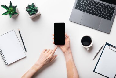Ofiste cep telefonu kullanan kadın elleri, üst görünüm, boş ekran