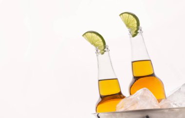 Soğuk içecek. Hafif biralı şeffaf bira şişeleri ve buzlu metal kovada bir dilim limon.