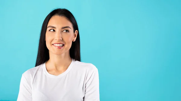 Happy woman biting lip and looking at copy space — Stock Photo, Image