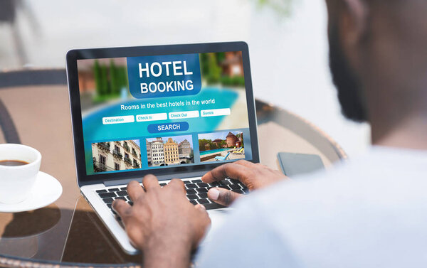 Черный мужчина отдыхает в кафе и бронирует отель онлайн
