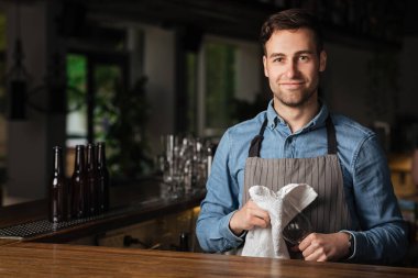 Barda servis. Barmen barın içindeki boş bardakları siliyor.