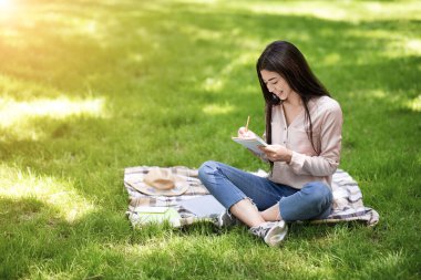 Parktaki sınavlara hazırlanan Asyalı öğrenci notlara notlar yazıyor.