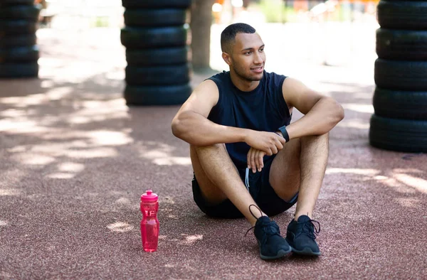 Bonito negro em sportswear descansando na pista de jogging no parque urbano, espaço em branco — Fotografia de Stock