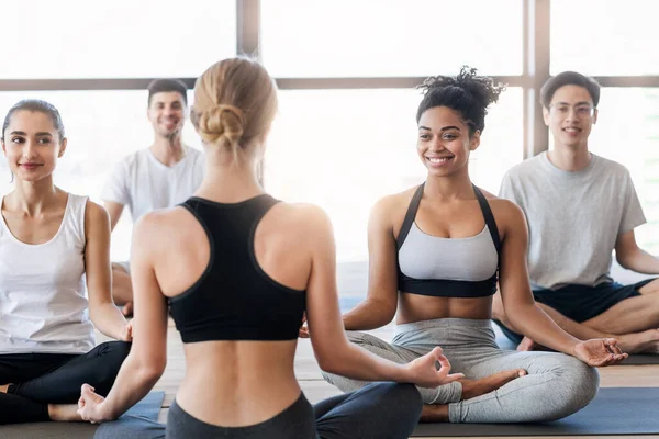 Giovani sportivi che praticano yoga con istruttore, rendendo facile sedersi posa — Foto Stock