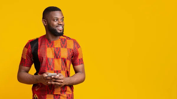 Glada svart man i afrikanska kostym innehav smartphone — Stockfoto