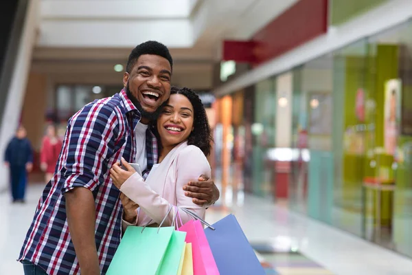 Happy Buyers. Cheerful African Couple Posing In Department Store After Successful Shopping