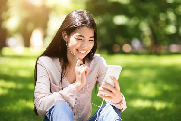 Joyful coreean fata having video apel pe smartphone în timp ce relaxare în parc — Fotografie, imagine de stoc