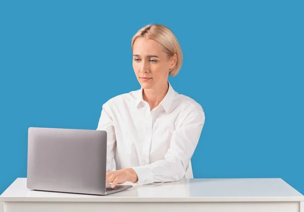 Žena kancelář pracovník pomocí notebooku na stole na modrém pozadí — Stock fotografie