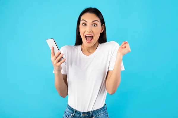 Young excited woman using mobile phone at studio — Stock Photo, Image