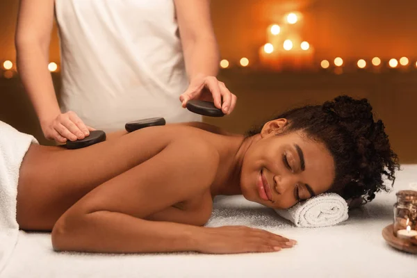 Masseuse putting black stones on lady back — Stock Photo, Image