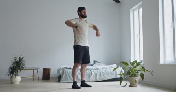 Actieve duizendjarige man oefenen handen op slaapkamer interieur — Stockvideo