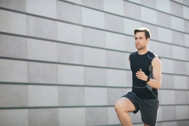 Şehirde spor haberleri. Spor giyimli genç bir adam ve spor takip cihazı çalışıyor.