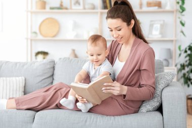 En iyi Bebek Kitapları. Sevgi dolu anne, küçük oğluna evde kitap okuyor.