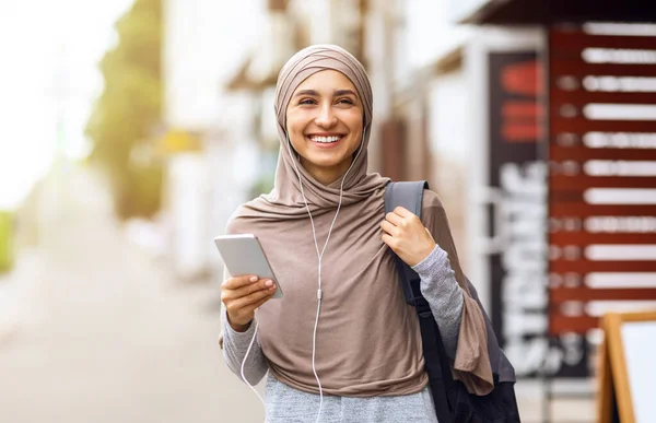 Chica árabe alegre caminando por la ciudad y escuchando música — Foto de Stock