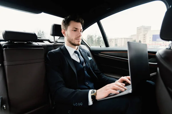 Occupato uomo d'affari che utilizza il suo computer portatile in auto di lusso — Foto Stock