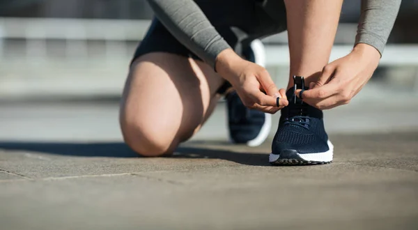Утренняя пробежка Молодой человек завязывает шнурки на кроссовках, на трассе — стоковое фото