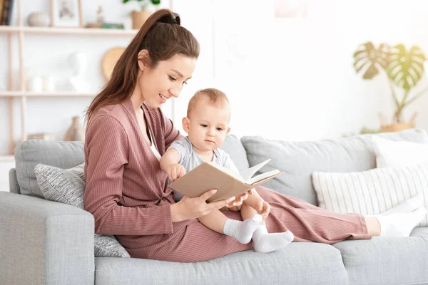 Annesinin evde sevgili bebeğine sesli bir şekilde kitap okuması. — Stok fotoğraf