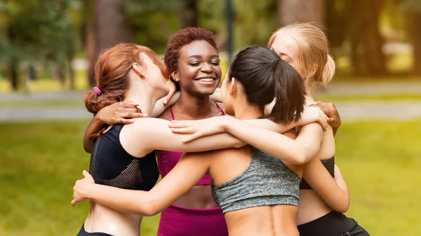 Multinacionais mulheres abraçando após o treinamento de ioga da manhã no parque — Fotografia de Stock