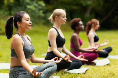 Yoga pratiği üzerine meditasyon yapan ya da nefes egzersizleri yapan çok uluslu kadınlar, boş alan.
