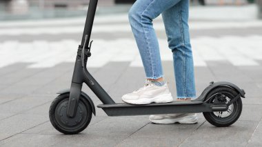 Dışarıda, elektrikli scooter 'ın üstünde duran bir kız.