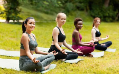 Spor giyim sektöründe güzel yeşil parkta yoga meditasyonu yapan güzel hanımlar.