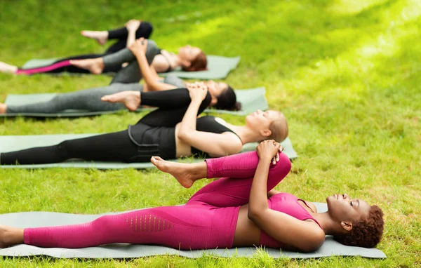 Group of diverse girls stretching their leg during yoga class outside, copy space — Stock Photo, Image