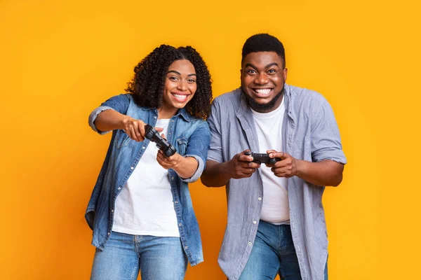 Entretenimento de casal. Jogos de azar casal preto jogando jogos de vídeo com Joysticks juntos — Fotografia de Stock