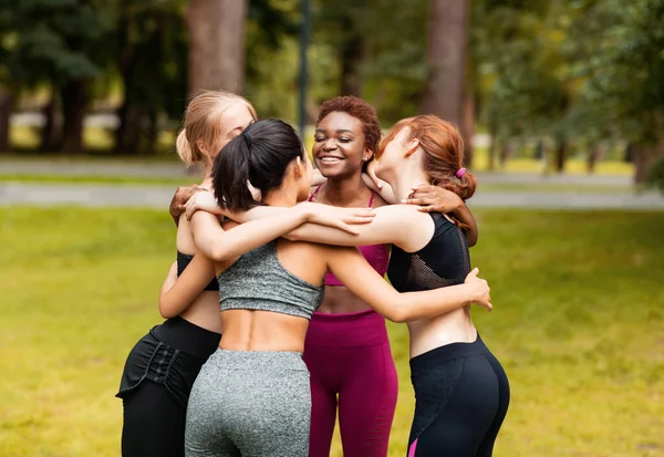 Různé mladé dívky ve sportovním oblečení objímání po venkovní jóga třídy v parku — Stock fotografie