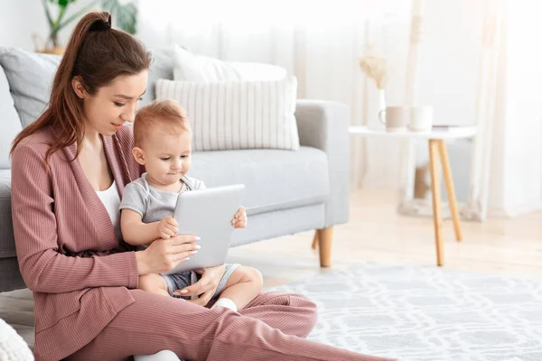 Dispositivos electrónicos para bebés. Mamá e hijo pequeño usando tableta digital en casa — Foto de Stock