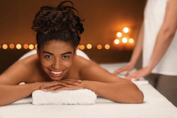 Mulher africana feliz frequentando spa, terapeuta irreconhecível de lado — Fotografia de Stock
