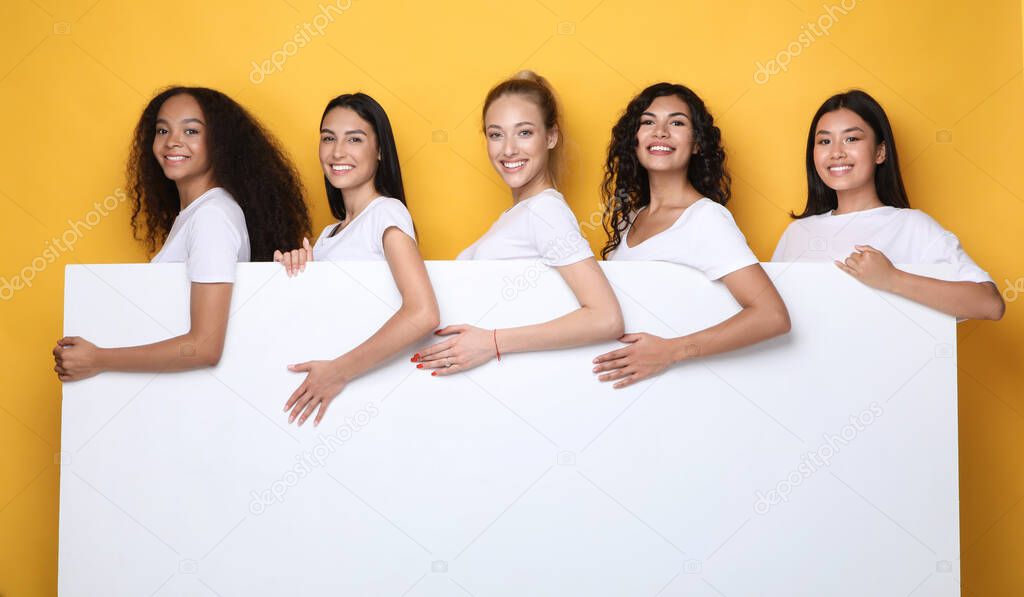 Happy Women Holding Poster For Text Standing In Studio, Mockup