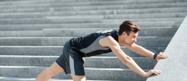 Spor yapan bir sporcu. Spor kıyafetli adam merdivenlerde şınav çekiyor.