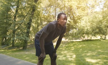 Yorgun Afrikalı Amerikalı koşucu parkta mola veriyor.