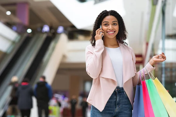 Shopaholiskt. Vacker svart kvinna promenader i Shopping Mall och prata på mobiltelefon — Stockfoto