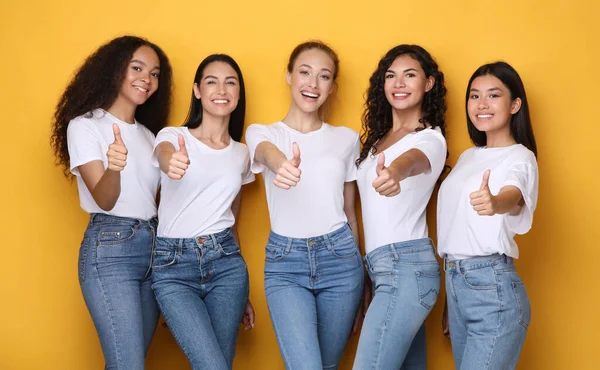 Multiethnic Women Gesturing Thumbs-Up Smiling To Camera Standing In Studio — Stock Photo, Image