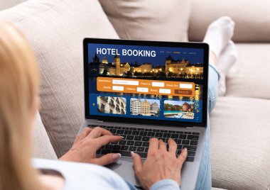 Evdeki kanepede uzanmış internetten otelleri kontrol eden bir kadın.