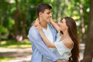 Genç evli çift sıcak bir yaz gününde dışarıda kucaklaşıyor, boş bir alan.