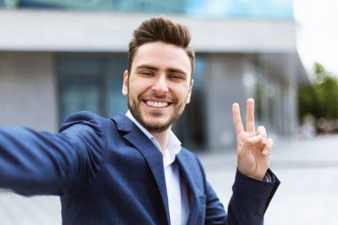 Gülümseyen genç işadamı görüntülü konuşma mı yapıyor yoksa şehir merkezinde selfie mi çekiyor?