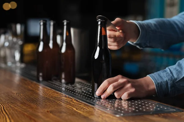 Barman handen open fles bier in een donkere bar interieur — Stockfoto