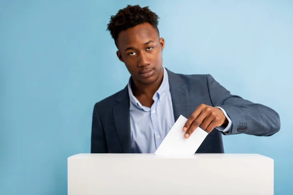 Un homme d'affaires afro-américain concentré tirant du papier lors du vote — Photo