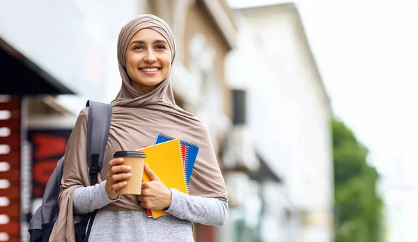 Chica musulmana feliz sosteniendo café para ir, yendo a la universidad — Foto de Stock