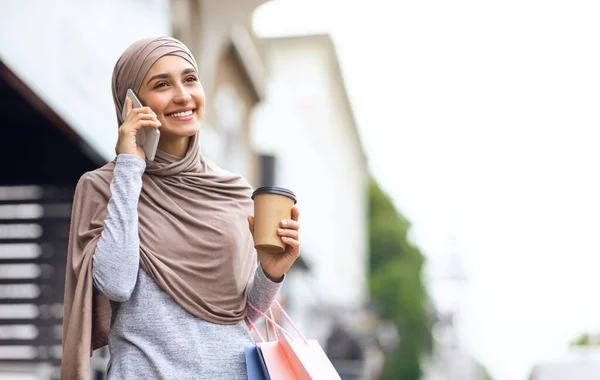 Alış veriş yapan neşeli Müslüman kadın akıllı telefondan konuşuyor. — Stok fotoğraf