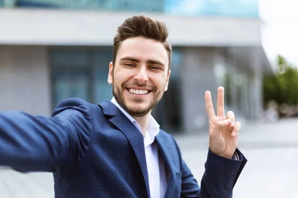 Lächelnder junger Geschäftsmann per Videochat oder Selfie in der Innenstadt — Stockfoto