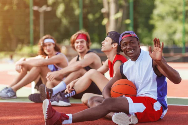 Feliz jugador de baloncesto afroamericano y su equipo multirracial relajarse después del partido en el estadio al aire libre, espacio libre — Foto de Stock